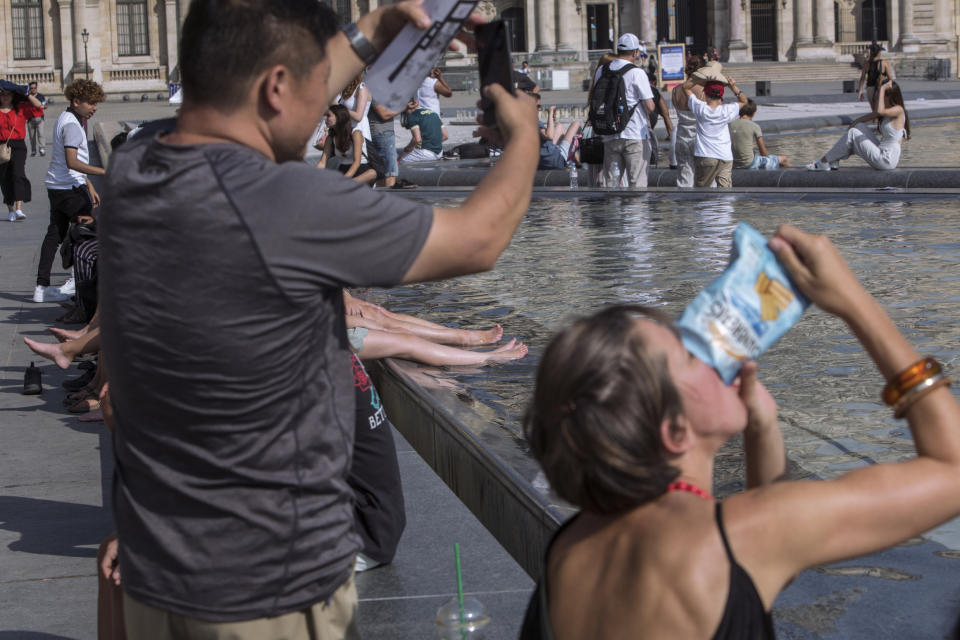 People cool off next to the fountains at Louvre Museum in Paris, France, Wednesday, July 24, 2019. Temperatures in Paris are forecast to reach 41 degrees C (86 F), on Thursday. (AP Photo/Rafael Yaghobzadeh)