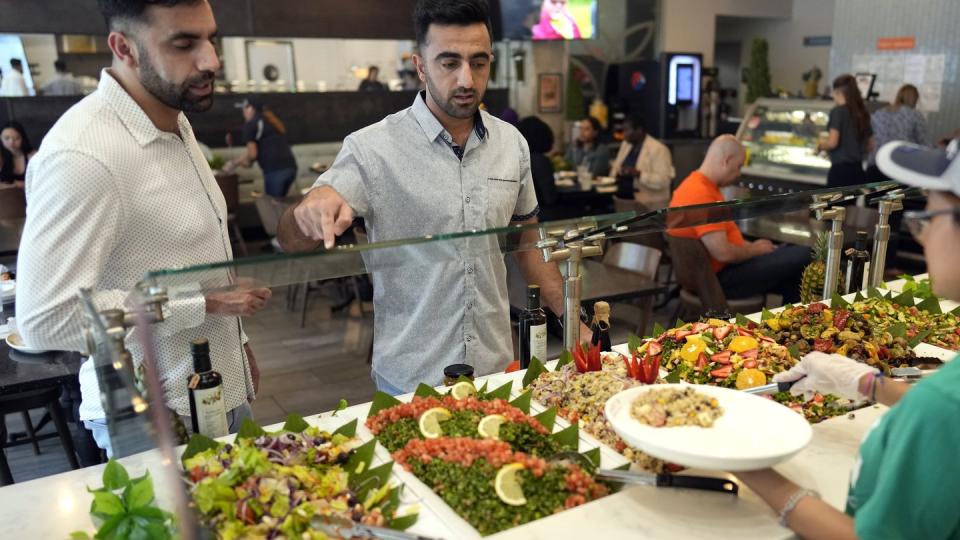 Abdul Wasi Safi, right, and his brother Samiullah pick out food for lunch, Wednesday, April 26, 2023, in Houston. (David J. Phillip/AP)