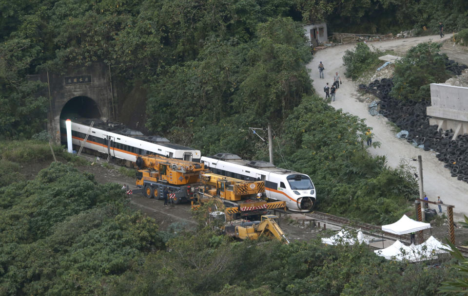 Rescue workers remove a part of the derailed train near Taroko Gorge in Hualien, Taiwan on Saturday, April 3, 2021. The train partially derailed in eastern Taiwan on Friday after colliding with an unmanned vehicle that had rolled down a hill, killing and injuring dozens. (AP Photo/Chiang Ying-ying)