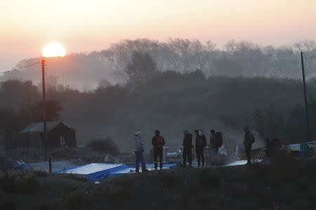 People look at tents and makeshift shelters at sunrise during the dismantlement of the camp called the "Jungle" in Calais, France, October 27, 2016. REUTERS/Philippe Wojazer