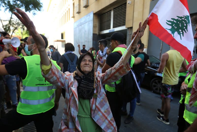 A demonstrator holds a Lebanese flag during a protest as Lebanese mark one year since the start of nation-wide protests in Beirut