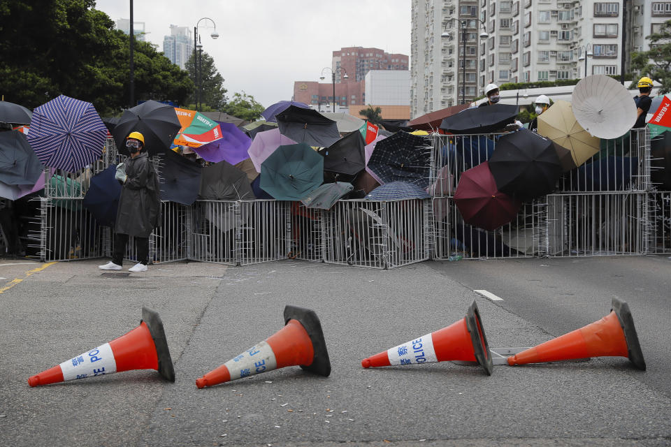 FILE - In this Sunday, July 14, 2019, file photo, protesters use umbrellas and steel barricades to block a road during a march through Sha Tin District in Hong Kong. While police put up barriers to deter demonstrators, protesters built their own barricades to protect themselves, block roads and prevent lawmakers from reaching the legislature. Like their shields, the protesters' barricades are often repurposed materials, such as fences used to separate traffic lanes.(AP Photo/Kin Cheung, File)