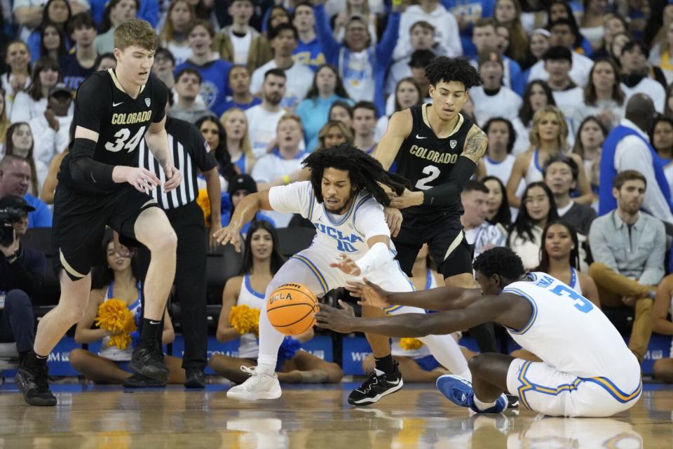 The Bruins' Tyger Campbell (10) and Adem Bona (3) reach for a loose ball Jan.14, 2023.