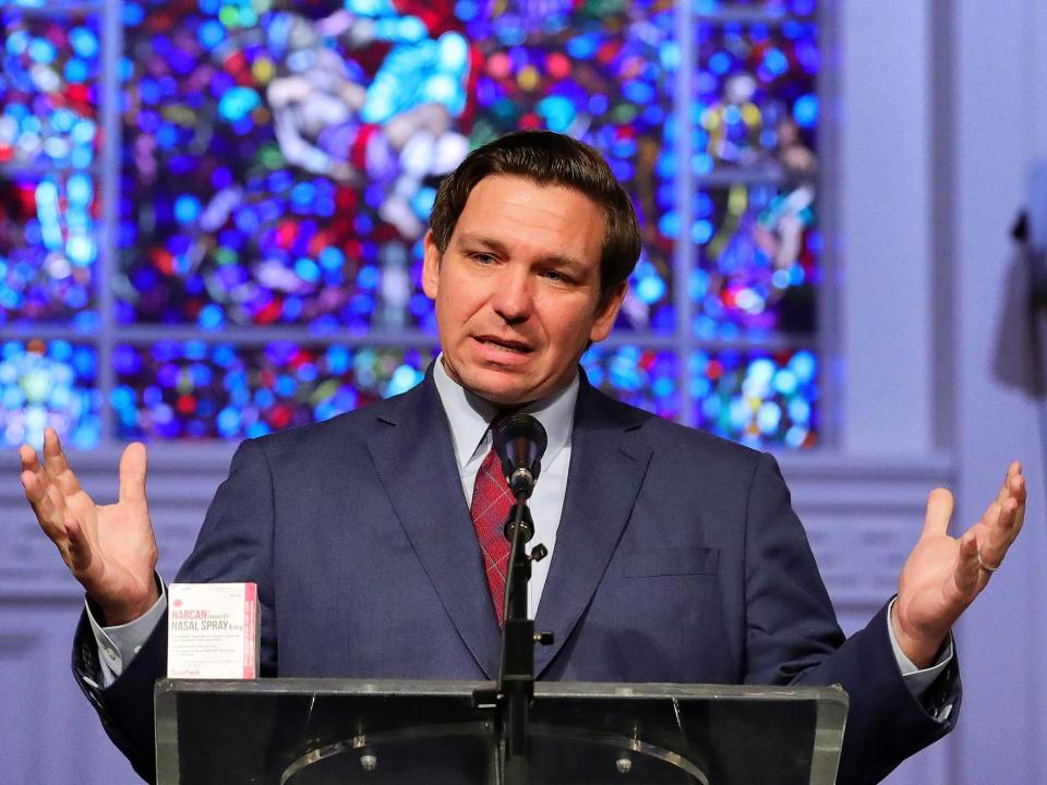 Ron DeSantis at church podium, hands out, with stained glass behind him