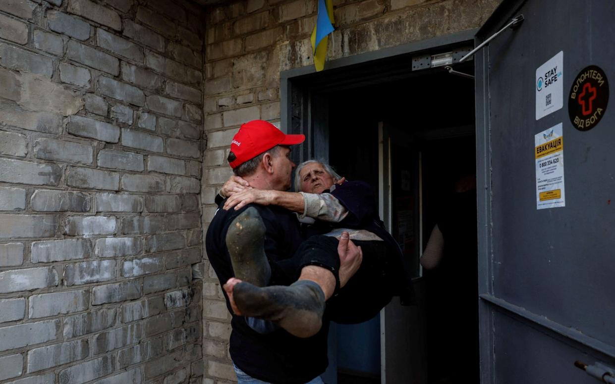 Yevhen Tkachov, 54, carries Nelia, 85, to a shelter for internally displaced people (IDPs) in Kostiantynivka, Ukraine