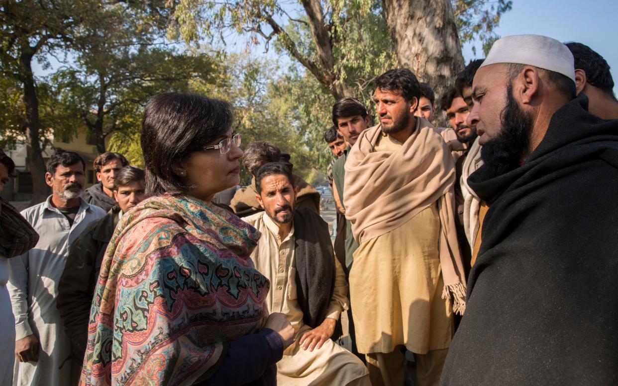 Dr Sania Nishtar, chair of the Benazir Income Support Programme, speaks to workers about their hardships as they gather outside a free communal kitchen for a meal - Saiyna Bashir