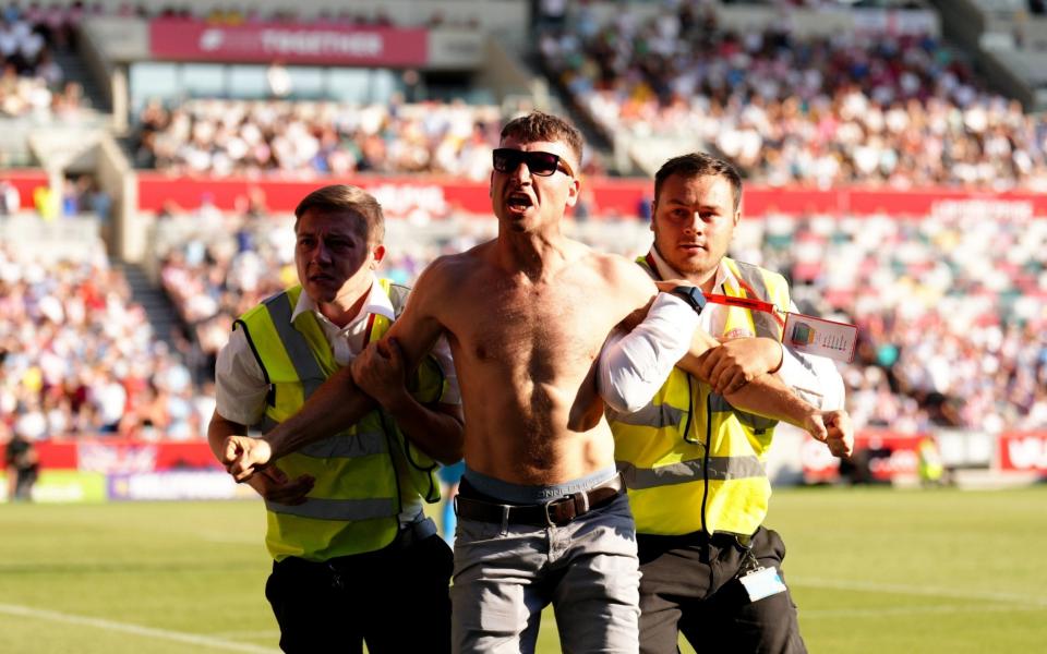 A pitch invader is taken away by security - John Walton/PA