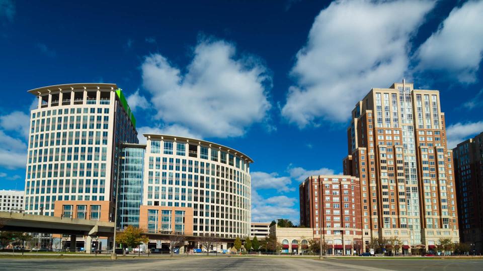 An office highrise building (left) and a highrise residential building (right) in Alexandriaâ€™s Carlyle neighborhood, with dramatic clouds in the background.