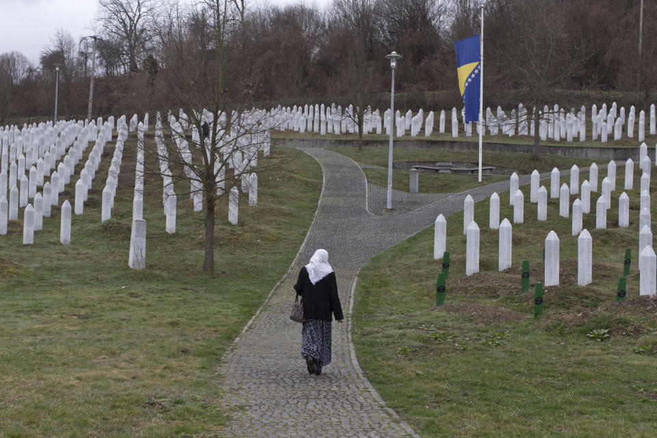 A woman walks through the cemetery of the Potocari memorial center for victims of the Srebrenica genocide in Potocari, Bosnia and Herzegovina, Wednesday, March 20, 2019. United Nations appeals judges on Wednesday upheld the convictions of former Bosnian Serb leader Radovan Karadzic for genocide, war crimes and crimes against humanity, and increased his sentence from 40 years to life imprisonment. (AP Photo/Marko Drobnjakovic)