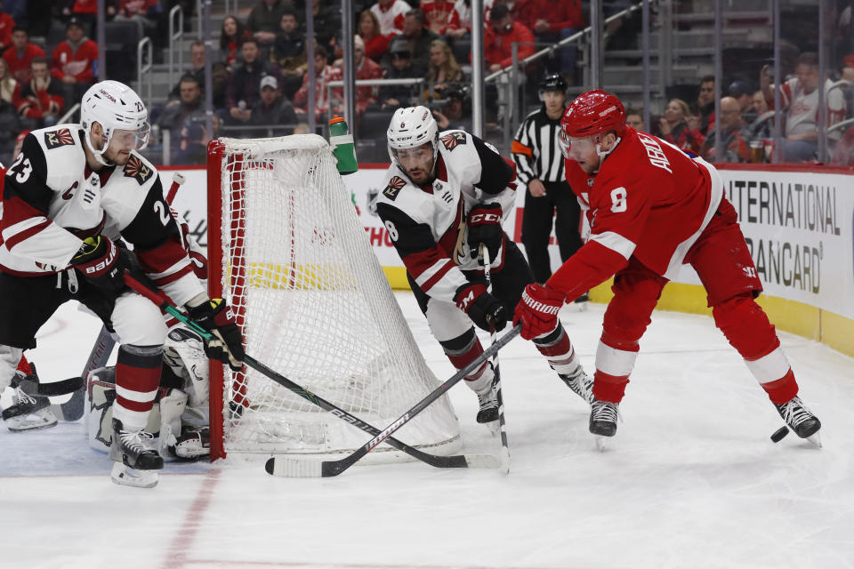 Detroit Red Wings left wing Justin Abdelkader (8) loses control the puck as Arizona Coyotes defenseman Oliver Ekman-Larsson (23) and center Nick Schmaltz (8) defend during the first period of an NHL hockey game, Sunday, Dec. 22, 2019, in Detroit. (AP Photo/Carlos Osorio)