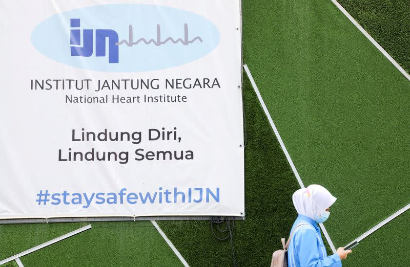 A woman walks past the logo of the National Heart Institute in Kuala Lumpur