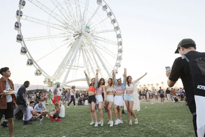 Festivalgoers posing in front of a ferris wheel at Coachella.