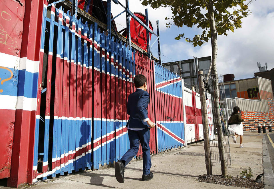 A child runs past a Union flag painted gate at a scrap dealer yard in east London