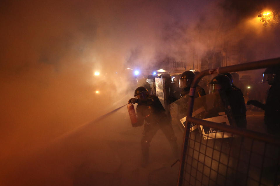 A policeman uses a fire extinguisher on a burning barricade during clashes with protestors in Barcelona, Spain, Tuesday, Oct. 15, 2019. (Photo: Emilio Morenatti/AP)