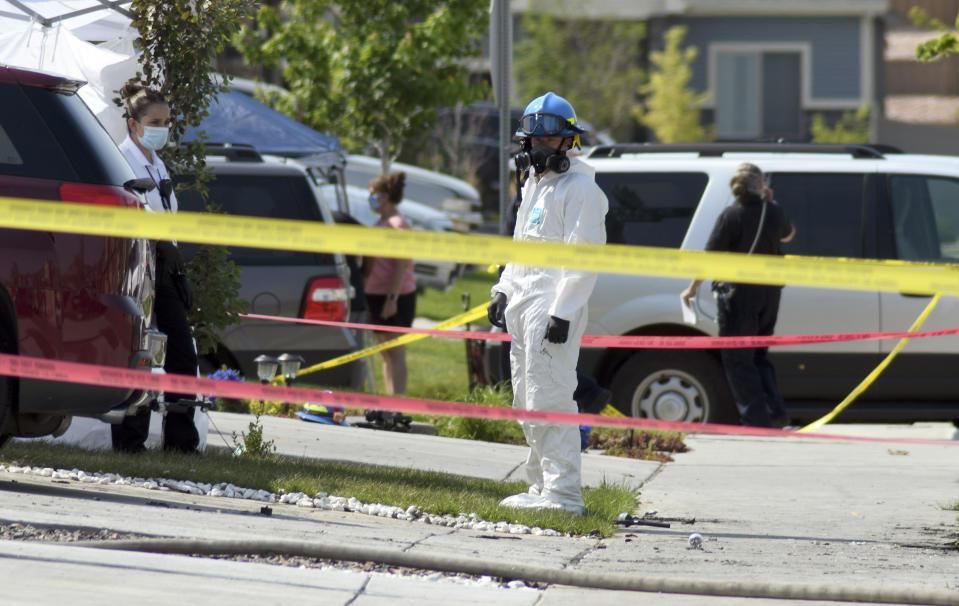 Investigators stand outside the remnants of a house fire that killed at least five people in suburban Denver on Wednesday, Aug. 5, 2020. Three people escaped the fire by jumping from the home's second floor. Investigators believe the victims were a toddler, an older child and three adults. Authorities suspect was intentionally set. (AP Photo/Thomas Peipert)