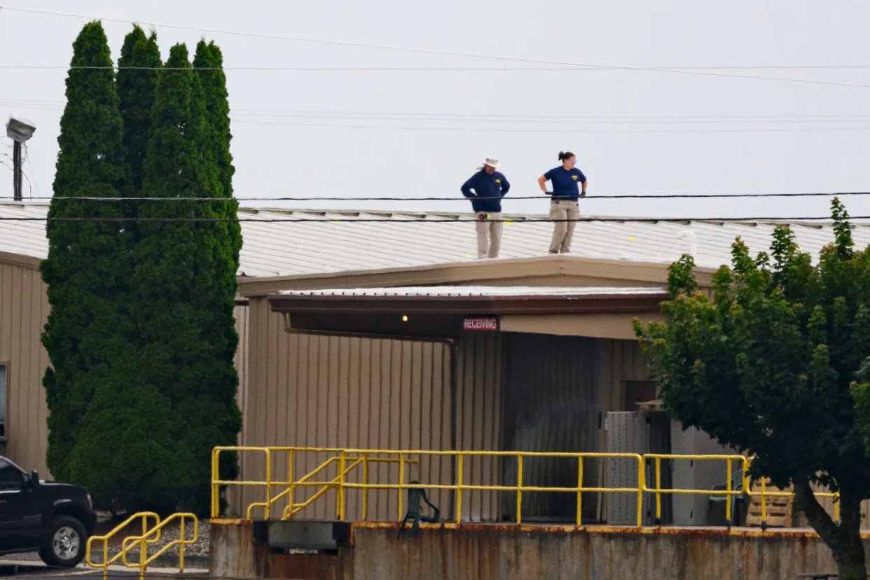 Two FBI investigators scan the roof of AGR International, adjacent to the Butler Fairgrounds in Butler, Pa., from which Matthew Thomas Crooks fired at Donald Trump on July 13. (Jeff Swensen / Getty Images)