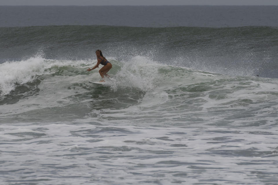 Una mujer surfea en la playa El Tunco antes de la llegada del huracán Julia, el domingo 9 de octubre de 2022, en La Libertad, El Salvador. (Foto AP/Moisés Castillo)