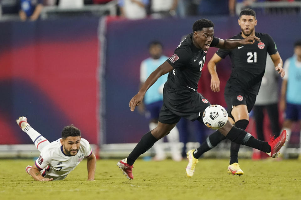 Canada forward Jonathan David, center, moves the pall past United States midfielder Christian Roldan, left, during the second half of a World Cup soccer qualifier Sunday, Sept. 5, 2021, in Nashville, Tenn. (AP Photo/Mark Humphrey)