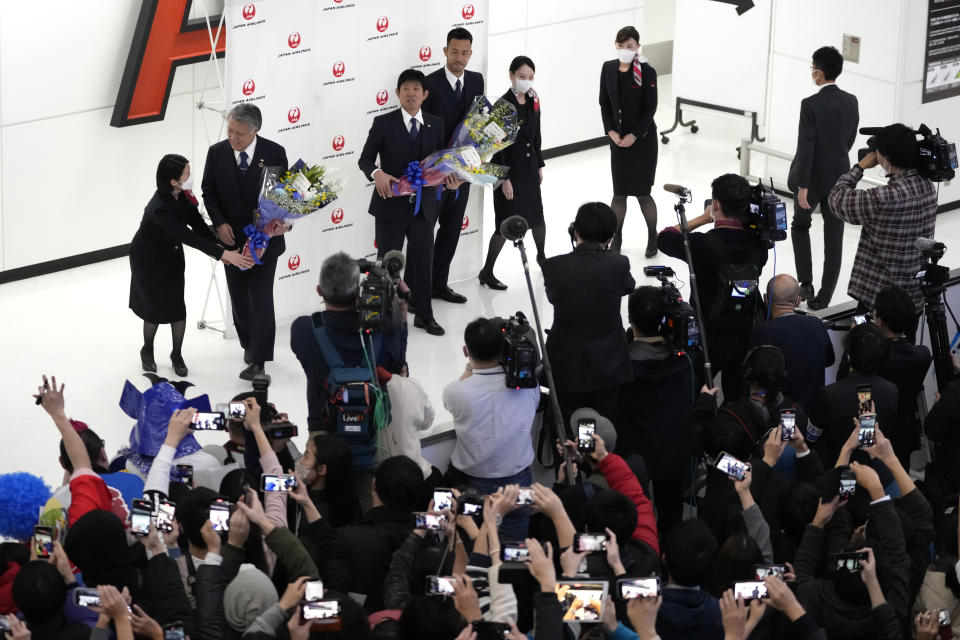 Japan's head coach Hajime Moriyasu, center and captain Maya Yoshida, center right, receive flowers as supporters welcome home the Japanese national soccer team from the World Cup in Qatar at Narita International Airport in Narita, east of Tokyo, Wednesday, Dec. 7, 2022. (AP Photo/Shuji Kajiyama)