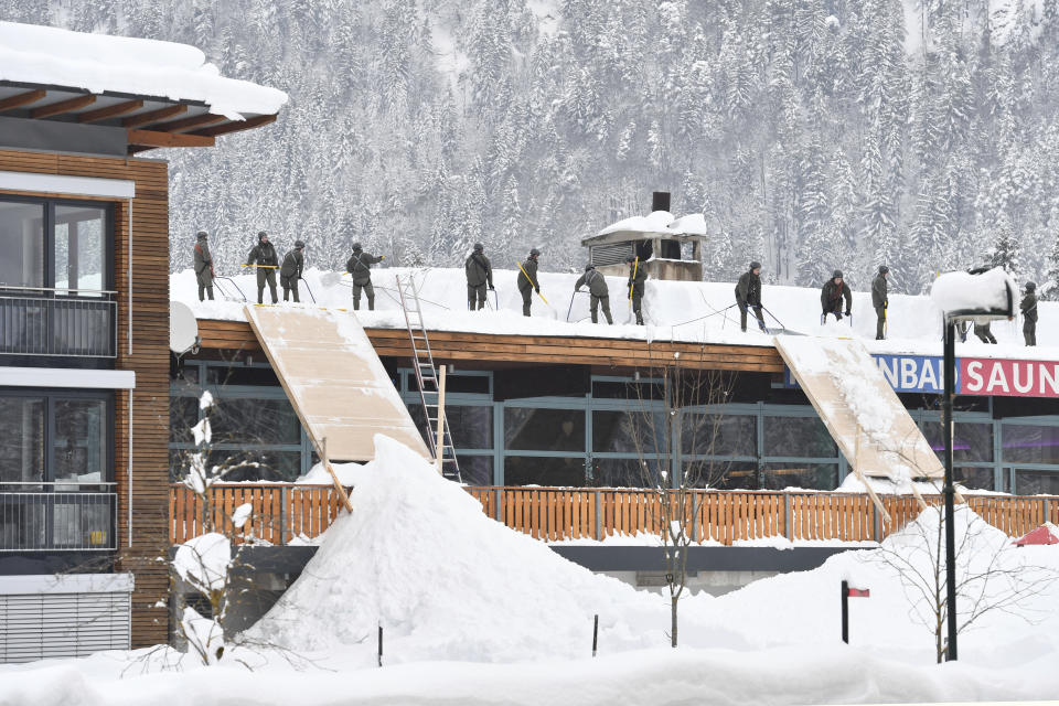 Solidiers from the Austrian Bundesheer clean a roof from snow on Saturday, Jan. 12, 2019 in Waidring. Austrian province of Tyrol.(AP Photo/Kerstin Joensson)