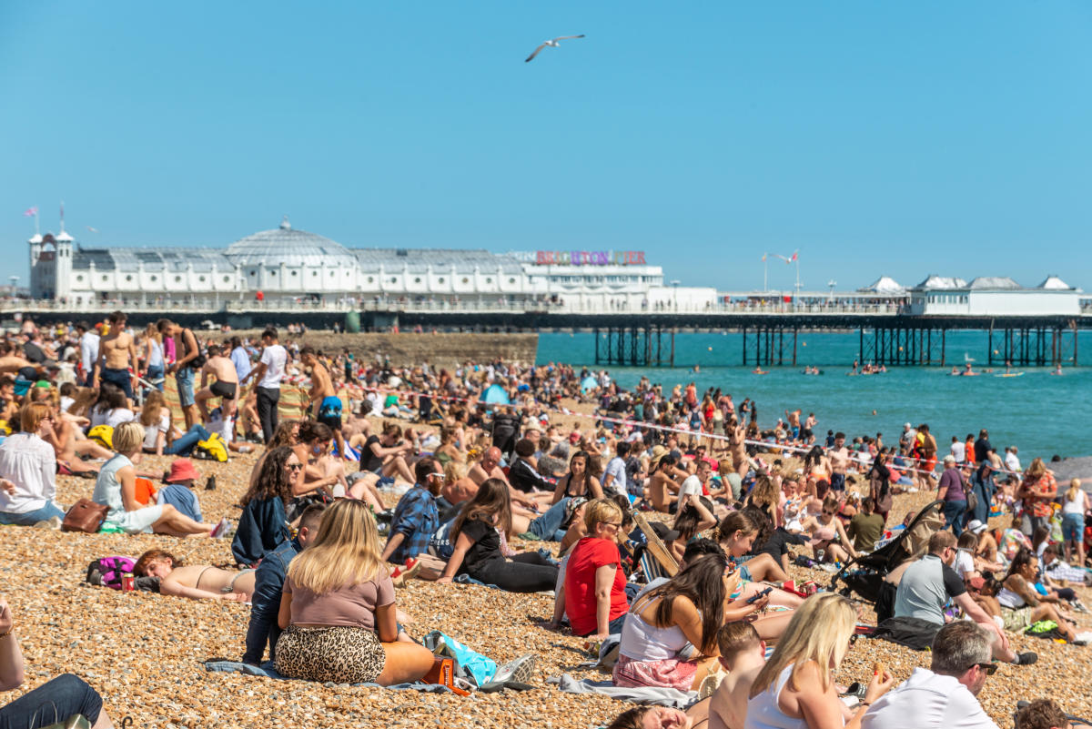 Man performs sex act on woman as she holds can of lager on beach photo