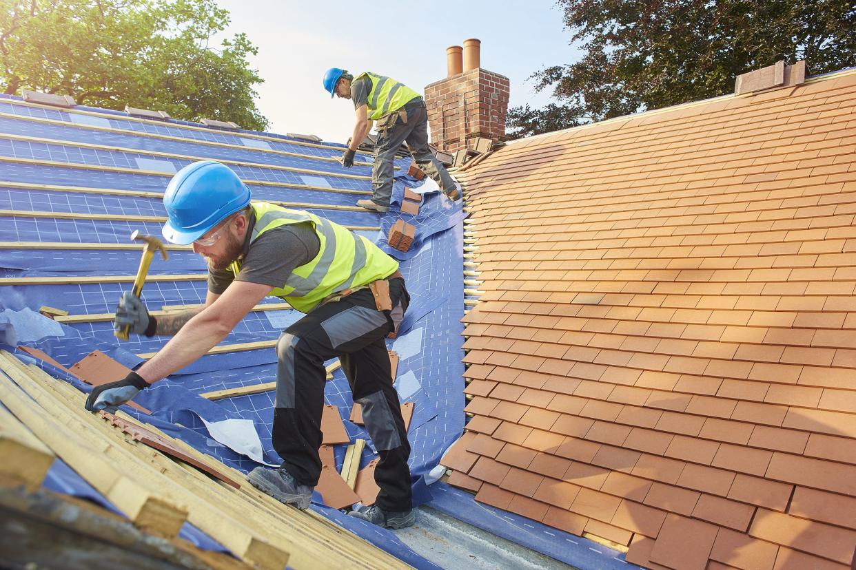 two construction workers installing roof on house