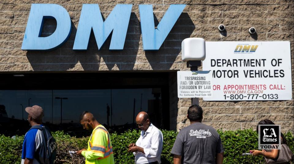 Five people in line outside a building with the letters "DMV" on it.