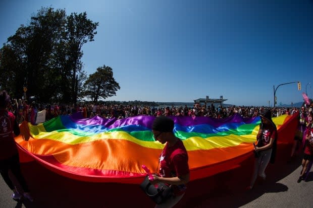 A large rainbow flag is carried by people marching in the 2019 Vancouver Pride Parade. The 2021 event will include many events, but not the typical parade. (Darryl Dyck/The Canadian Press - image credit)