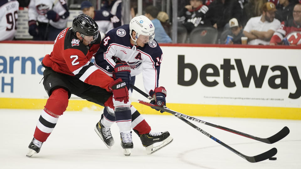 Columbus Blue Jackets defenseman Vladislav Gavrikov (4) and New Jersey Devils defenseman Colton White (2) fight for the puck during the second period of an NHL hockey game, Sunday, Oct. 30, 2022, in Newark, N.J. (AP Photo/Eduardo Munoz Alvarez)