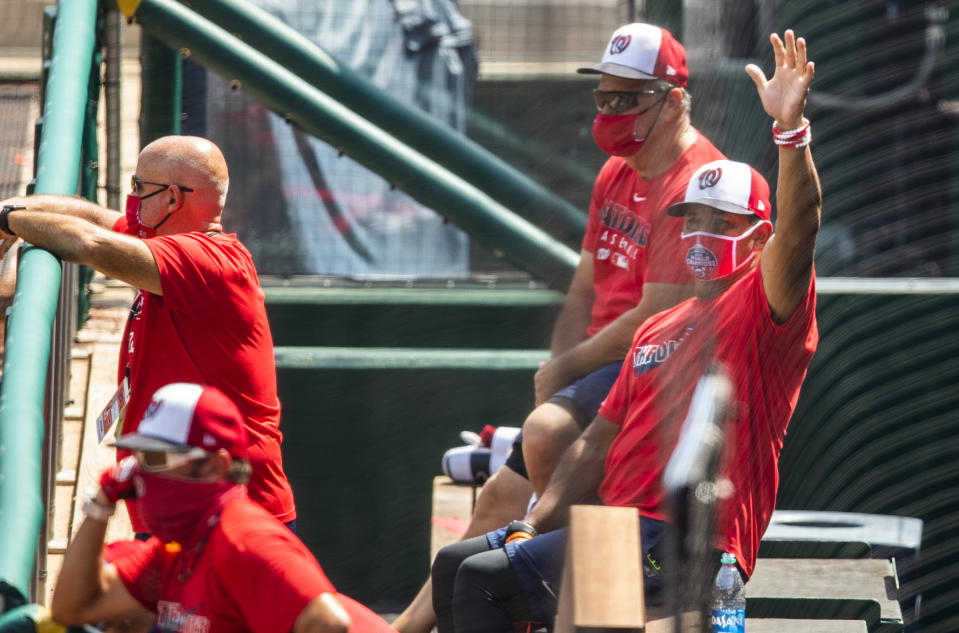 Washington Nationals manager Dave Martinez, right, with General Manager Mike Rizzo, back left, watch from the dugout a baseball intrasquad game at Nationals Park, Sunday, Aug. 2, 2020, in Washington. (AP Photo/Manuel Balce Ceneta)