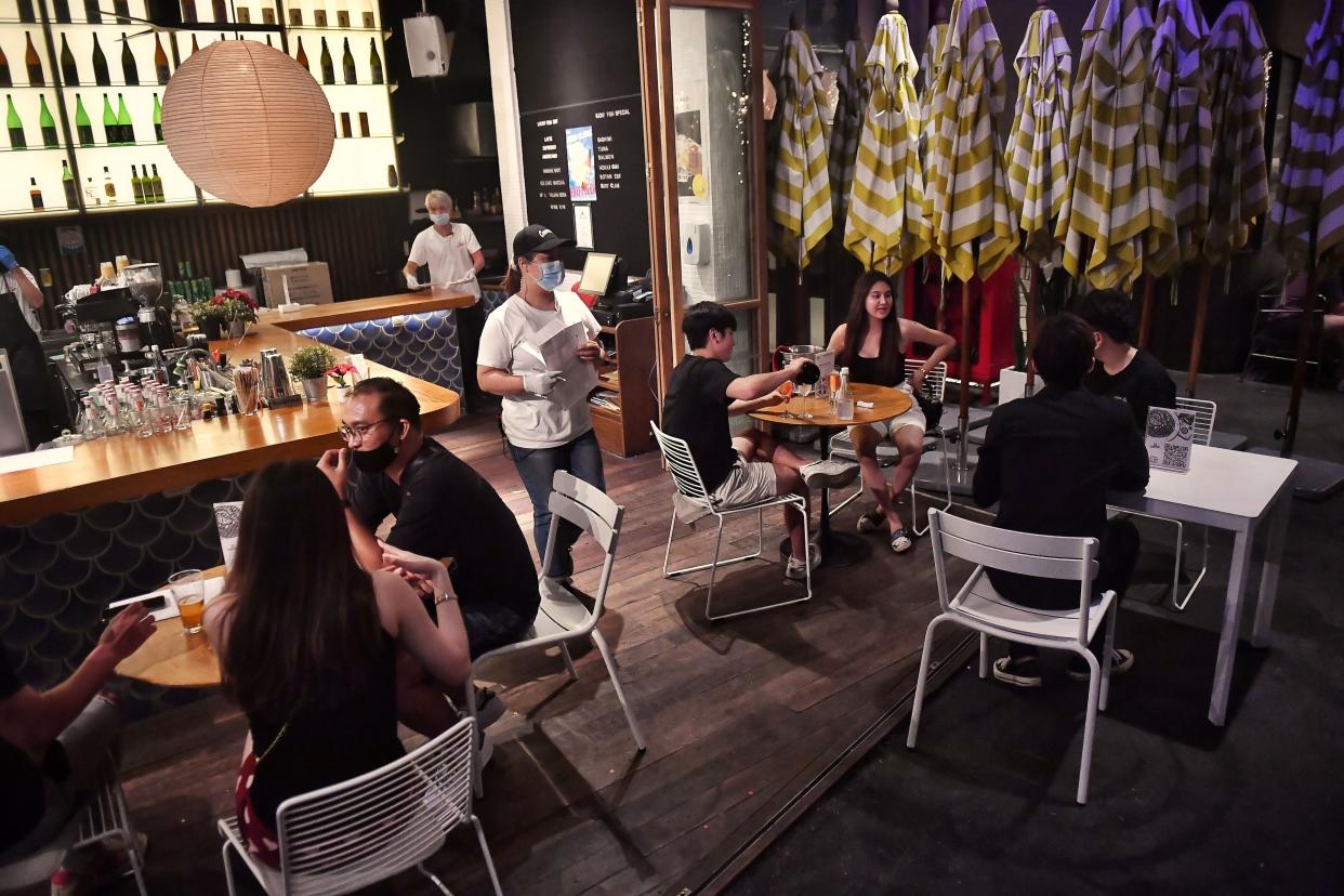 A waiter serves customers at a bar as restrictions to halt the spread of the coronavirus are eased in Bangkok on July 1, 2020.