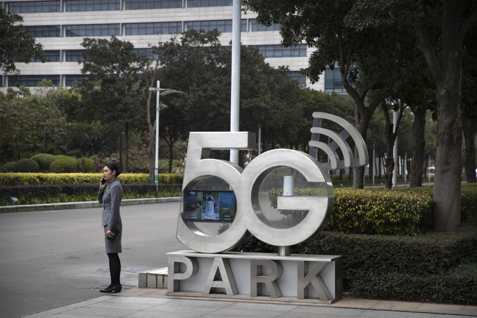 A Huawei employee talks on her cellphone as she stands next to a sign at Huawei's campus in Shenzhen in southern China's Guandong Province, Thursday, Dec. 5, 2019. Chinese tech giant Huawei is asking a U.S. federal court to throw out a rule that bars rural phone carriers from using government money to purchase its equipment on security grounds. (AP Photo/Mark Schiefelbein)