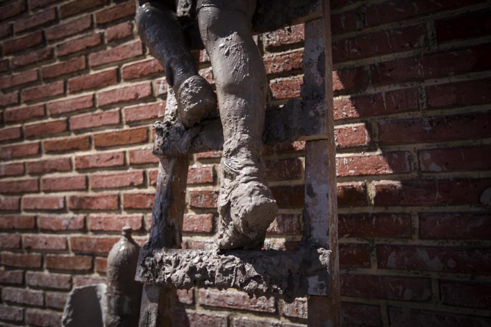 In this Jan. 13, 2017 photo, a local resident climbs a ladder as he carries his belongings to the roof of his mud damaged home, in the town of Volcan , Jujuy province, Argentina. Authorities declared the area a disaster zone after the town was hit by a mudslide one week ago, that covered it in a thick layer of mud. (Gianni Bulacio/Infoto via AP)