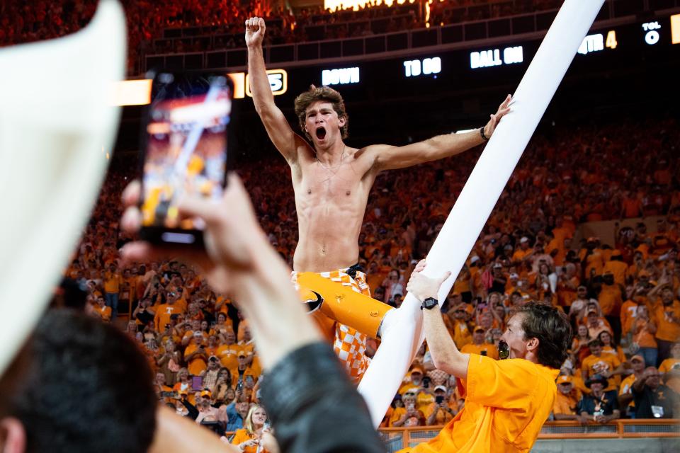 A Tennessee fan cheers after climbing the downed goalpost.