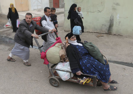 A man pushes an old woman in a cart in Mosul, Iraq, November 16, 2016. REUTERS/Goran Tomasevic