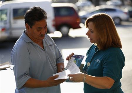 Engrith Acosta, patient care coordinator at AltaMed, speaks to a man during a community outreach on Obamacare in Los Angeles, California November 6, 2013. REUTERS/Mario Anzuoni