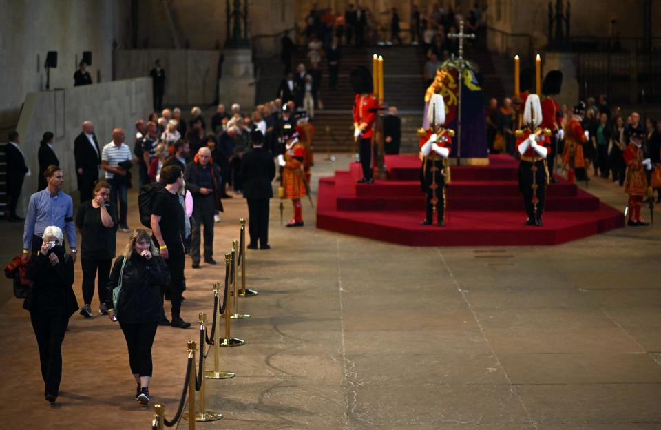 Members of the public pay their respects as they pass the coffin of Queen Elizabeth II as it Lies in State inside Westminster Hall, at the Palace of Westminster in London on September 14, 2022. - Queen Elizabeth II will lie in state in Westminster Hall inside the Palace of Westminster, from Wednesday until a few hours before her funeral on Monday, with huge queues expected to file past her coffin to pay their respects.