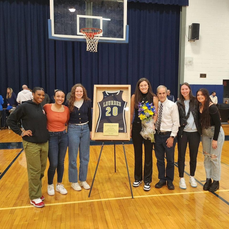 Dallas Wings player Maddy Siegrist poses next to her retired high school basketball jersey alongside her former Our Lady of Lourdes coach and teammates during a Jan. 5, 2024 ceremony.