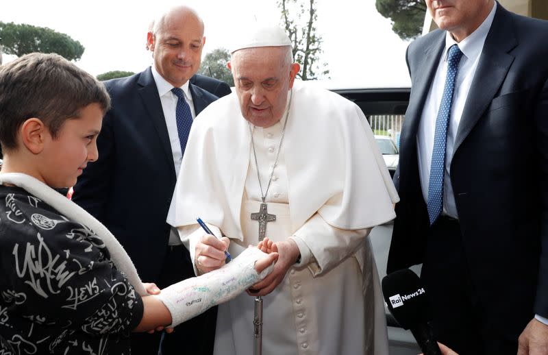 El papa Francisco escribe sobre el yeso de un niño cuando sale del hospital Gemelli de Roma en Roma, Italia