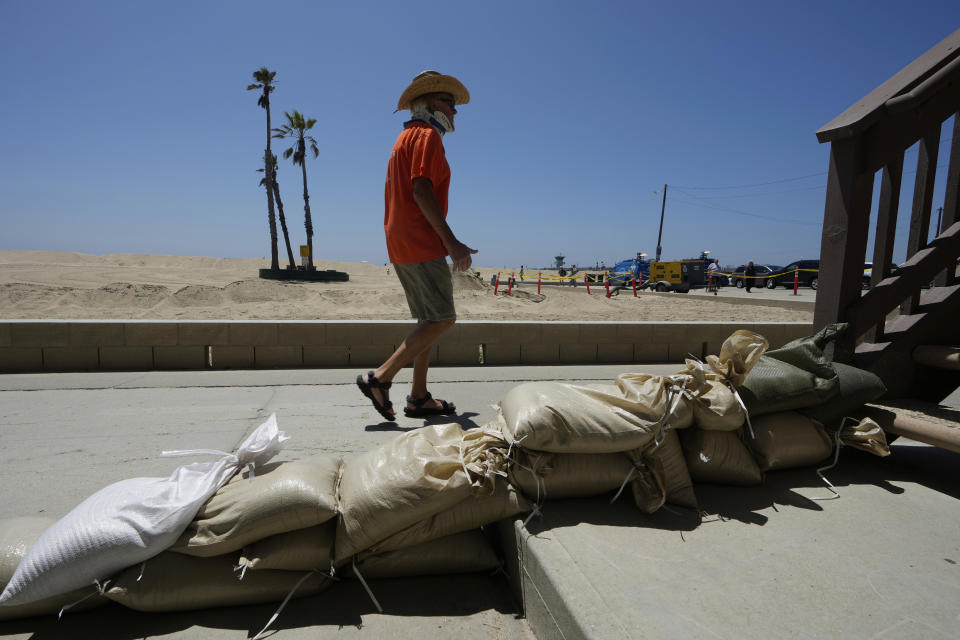 Tom Ostrom, residente en Seal Beach, pasa junto a una vivienda protegida con costales de arena, en Seal Beach, California, el 18 de agosto de 2023. (AP Foto/Damian Dovarganes)