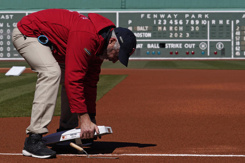 Grounds crew worker Jeff Avigian installs first base prior to the opening day of a baseball game between the Boston Red Sox and Baltimore Orioles, Thursday, March 30, 2023, in Boston. (AP Photo/Charles Krupa)