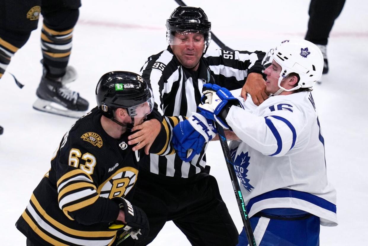 NHL linesman Jonny Murray, center, tries to separate Boston Bruins left wing Brad Marchand (63) and Toronto Maple Leafs right wing Mitch Marner (16) during the second period of Game 5 of an NHL hockey Stanley Cup first-round playoff series, Tuesday, April 30, 2024, in Boston. (Charles Krupa/Associated Press - image credit)