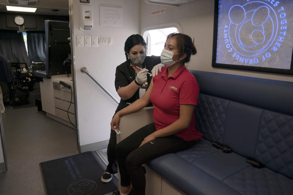 FILE - In this April 29, 2021, file photo, nurse Natasha Garcia administers a dose of the Moderna COVID-19 vaccine to Magaly Esparza in a mobile clinic set up in the parking lot of a shopping center in Orange, Calif. Teams of experts are projecting COVID-19's toll on the U.S. will fall sharply by the end of July, according to research released by the government Wednesday, May 5. (AP Photo/Jae C. Hong, File)