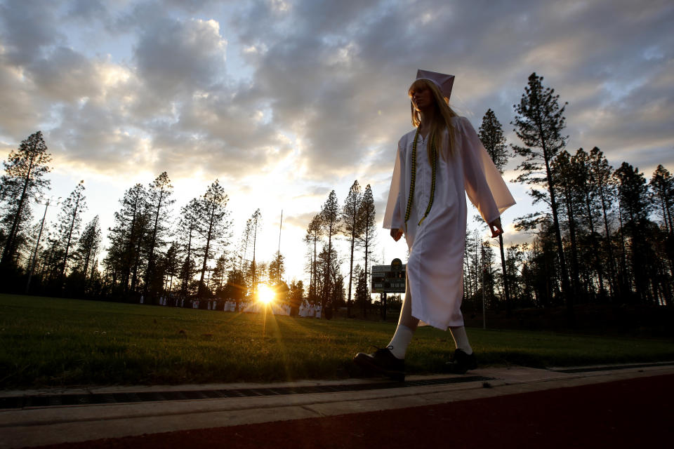 FILE - In this June 6, 2019, file photo, a graduating senior walks to the graduation ceremony at Paradise High School in Paradise, Calif. Months after most of the students of Paradise High lost their homes when the Camp Fire swept through the area, the seniors gathered one more time at the high school for graduation. Ceremonies will be held in Paradise, Friday, Nov. 8, 2019, to mark the one-year anniversary of the fire, including 85 second of silence to remember the 85 people who died. (AP Photo/Rich Pedroncelli, File)