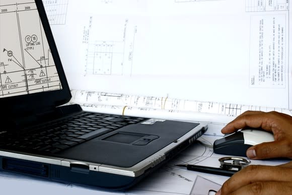 A man edits a design document on a laptop.