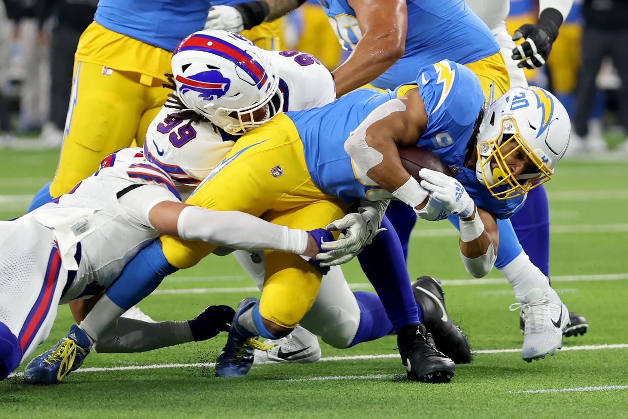 INGLEWOOD, CALIFORNIA - DECEMBER 23: Austin Ekeler #30 of the Los Angeles Chargers runs with the ball while being tackled by Tim Settle #99 of the Buffalo Bills in the first quarter at SoFi Stadium on December 23, 2023 in Inglewood, California. (Photo by Sean M. Haffey/Getty Images)