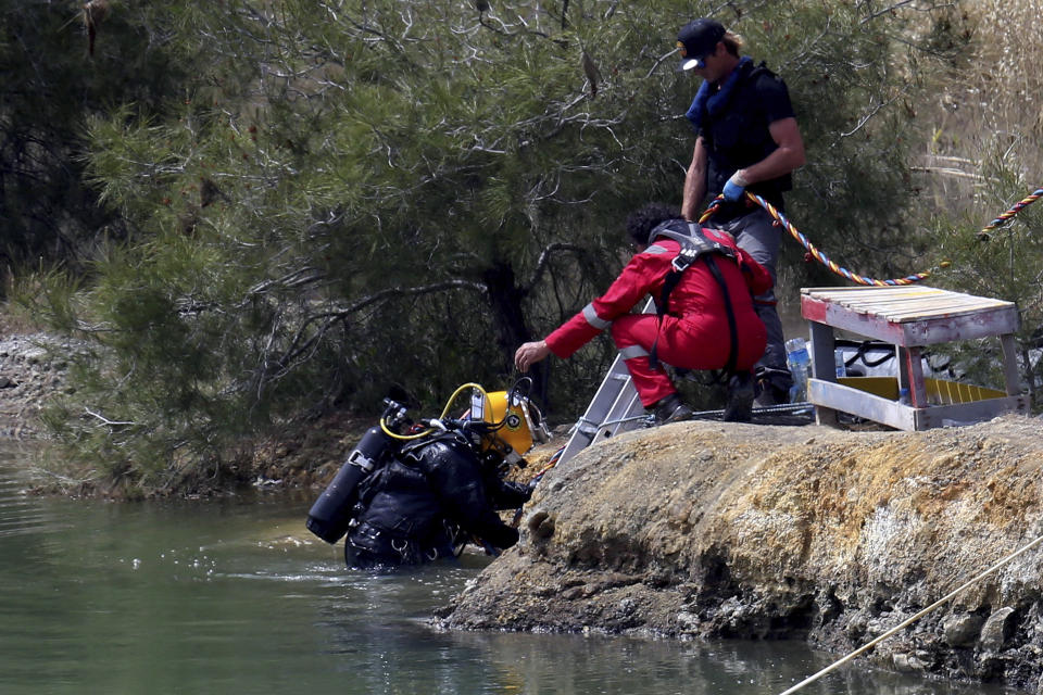 A diver gets out from a lake after searching for female bodies near the village of Xiliatos outside of capital Nicosia, Cyprus, Friday, April 26, 2019. Cyprus police are intensifying a search for the remains of more victims at locations where an army officer _ who authorities say admitted to killing five women and two girls _ had dumped their bodies. (AP Photo/Petros Karadjias)