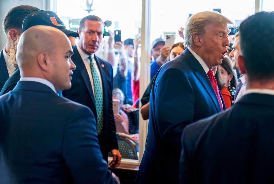 Former President Donald Trump's valet Walt Nauta, left, watches as Trump greets supporters at Versailles restaurant with Trump on Tuesday, June 13 in Miami. Nauta, a personal aide whom prosecutors say moved boxes from a storage room to Trump's residence for him to review and later lied to investigators about the movement, joined Trump on Tuesday in federal court.