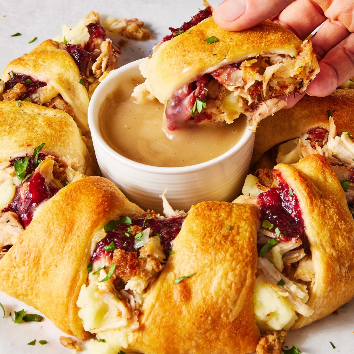 a ring of crescent dough surrounding traditional thanksgiving leftover ingredients like cranberry sauce and stuffing