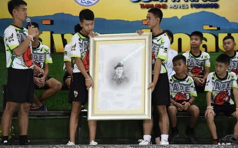 Rescued Thai football coach Ekkapol Chantawong (L) together with 12 children pays tribute to the Navy Seal who died during their rescue - Credit: AFP